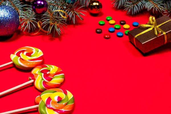 Flerfärgade klubbor och godis på en röd bakgrund med juldekoration, presenter och gran grenar. Banner en konditori konditori konditori — Stockfoto