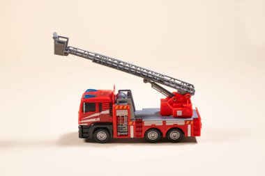 Bej arka plandaki oyuncak daktilo plastikten yapılmış kırmızı itfaiye aracı. Oyuncakçı için, oğlana bir hediye..