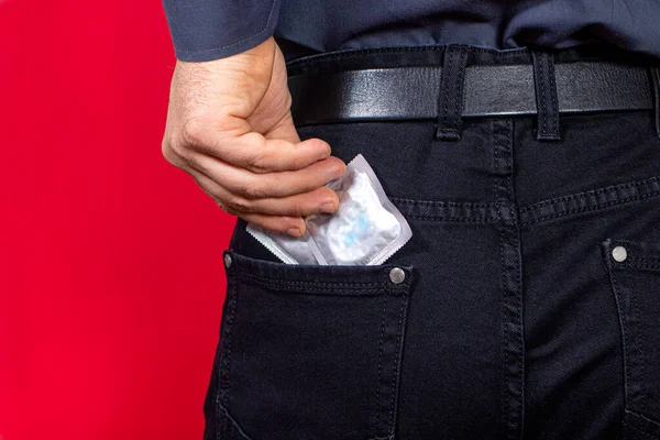 Man Pulls Out Package Condom Red Background Protected Sex Barrier — Stock Photo, Image