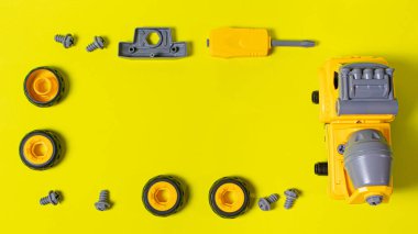 Oyuncak daktilo, sarı arka plandaki dişlileri döndüren beton karıştırıcı ve tornavidadır. Oyuncakçı ve eğitim faaliyetleri için fotoğraflar. Çocukların erken gelişimi