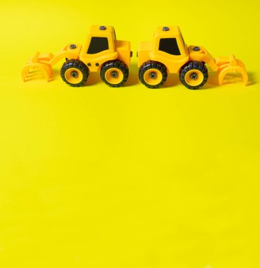 Sarı arka planda çocukların inşaat makinesinin seyir defteri yükleyicisi. Çocuk için traktör ve oyuncak mağazası için afiş için metin kopyalama alanı olan bir yer