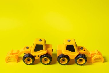 Sarı arka planda çocukların inşaat makinesinin seyir defteri yükleyicisi. Çocuk için traktör ve oyuncak mağazası için afiş için metin kopyalama alanı olan bir yer