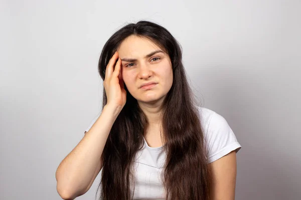 A tired woman holds her head with her hand, her head hurts. Brain vascular spasm, hypertension, high blood pressure after stress at work. Fatigue and excruciating headache — Stock Photo, Image