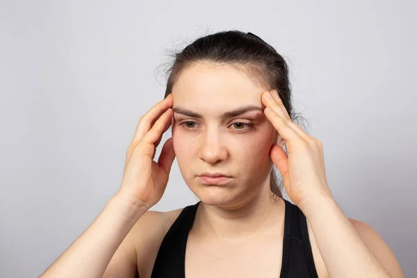 Hält das Mädchen ihre Hände am Tempel auf hellweißem Hintergrund. Konzentration, Konzentration und Meditation, Kopfschmerzen. Müder Blick — Stockfoto