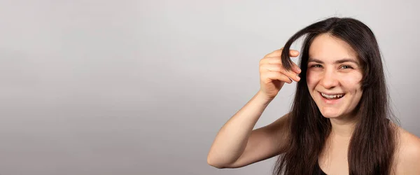 Una mujer está creciendo mucho. Cuidado del cabello, aceites y viales para el crecimiento del cabello. Cabello moreno saludable. Banner espacio de copia para la barbería de texto — Foto de Stock