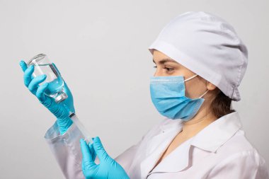 Hemşire şişeden şırıngaya sodyum klorür solüsyonu topluyor. Antibiyotik üretimi, aşılama, hastalıkların önlenmesi ve tedavisi.