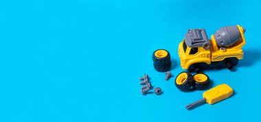 Mavi arka planda plastikten yapılmış, metin kopyalamak için yeri olan sarı makine beton karıştırıcı. Çarklı ve tornavidalı oyuncaklar. Detaylara ayrılabilir. Oyuncak tasarımcısı. Oyuncak mağazası için pankart.