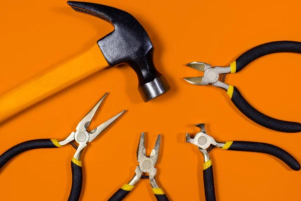 Construction tools hammer, pliers, cutters. tongs and round-the-heads on a orange background. Banner for construction store and repair, locksmith.