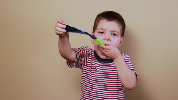 子供は笛をチューブ、熱、歯に笛を吹く。縞模様のTシャツを着た男の子の子供たちの喜び. — ストック動画