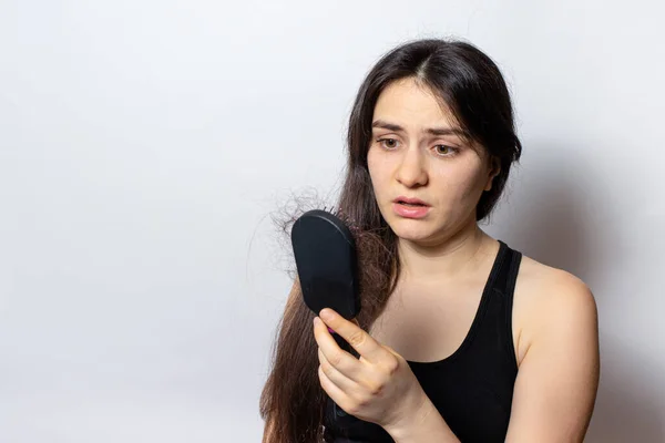 La chica sostiene un peine para el pelo con el pelo caído. Pérdida de cabello, cuidado del cabello. — Foto de Stock