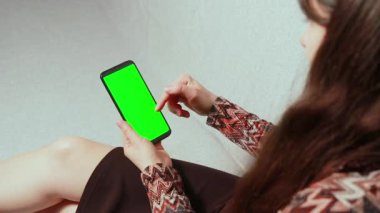 İnternette bir kadın telefonda reklam okuyor, el hareketi yapıyor. Video Chromakey Yeşil Ekran. Haberler ya da Reklamlar. Kaydırır, ekrana basar, yakınlaştırır ve ekranı kapatır