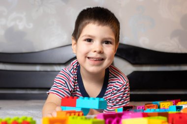 3-4 yaşında bir çocuk renkli inşaat bloklarıyla yatakta oynuyor. Anaokulu çocukları için eğitim oyunları. Oyuncakçı, kreş ya da anaokulu için..