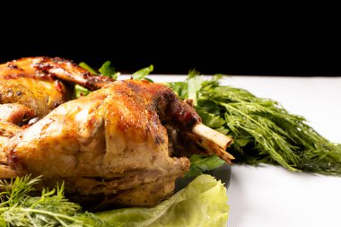 Sebzelerle pişirilmiş tavşan eti ve siyah beyaz arka planda bir tabakta otlar.