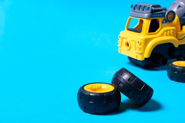 The toy car is a designer on a blue background. The wheels of the typewriter are spinning. Toy tire mount for a toy store or children\'s development center.