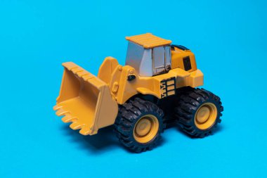 Oyuncak daktilo çekici buldozer mavi arka planda. Çocuklar için oyuncaklar.