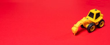 Kırmızı arka planda oyuncak traktör matkabı, metin için bir yer, oyuncak mağazası için bir pankart..