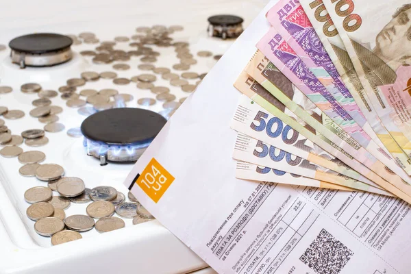 Banknotların ve ödeme emrinin hryvniaları, gaz ocağı ve sikkelerin arka planına karşı. Ukrayna 'da doğalgazın fiyatı, kamu hizmetlerinin fiyatlarında artış.