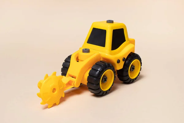 丸みを帯びた黄色いトラクターベージュの光の背景に木のためのノズルを見た おもちゃ屋の建設機械器具 — ストック写真