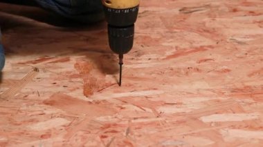 Adam tornavidayı yonga tahtasına sıkıştırıyor. Bir apartman ya da evin onarımı.