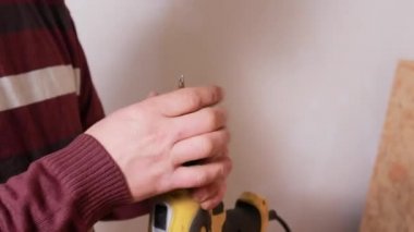 Erkek bir marangoz tornavida ile çalışır, hortumu aletin üzerine yerleştirir. Evler ya da daireler inşa edilecek.