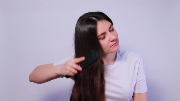 A lány egy hajkefét tart, kihulló hajjal, fésülködve és sikoltozva. Hajhullás, hajápolás. — Stock videók