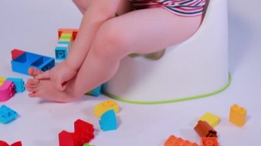 Küçük bir çocuk tencereye oturur ve çok renkli tasarımcı küpleriyle oynar. Esrara alışsan iyi olur..
