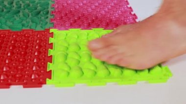 Bir adam ortopedik masaj çok renkli yapboz paspaslar üzerinde yürür. Yetişkinlerde düz taban önleme.