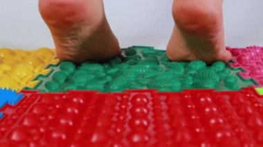 Kadın ortopedik renkli yapboz paspaslarda çoraplarla yürüyor. Düz taban, ayak kasları eğitimi ve yetişkinlerde ayak masajı.