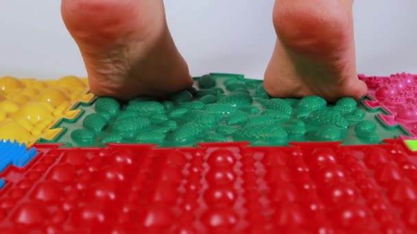 La donna cammina su calzini su stuoie di puzzle colorate ortopediche. Prevenzione dei piedi piatti, formazione dei muscoli del piede e massaggio ai piedi negli adulti — Video Stock