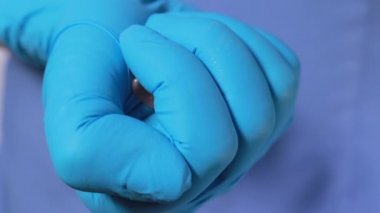 Dişçinin elinde seramik yapay takma diş var. Diş protezi, doktorun eldivenli ellerinde. Diş hekiminin kavramsal fotoğrafı. Protez dişçilik. Takma diş.