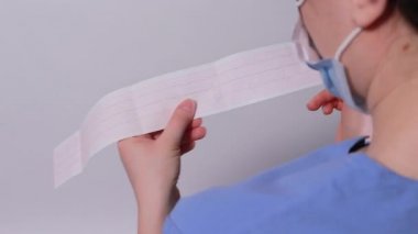 Kardiyolog akut miyokardiyal enfarktüsü olan bir hastanın elektrokardiyogramını gösteriyor. Kalp ve kardiyovasküler hastalıklar, kardiyoloji ve kardiyografi