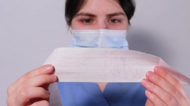 Kardiyolog akut miyokardiyal enfarktüsü olan bir hastanın elektrokardiyogramını gösteriyor. Kalp ve kardiyovasküler hastalıklar, kardiyoloji ve kardiyografi