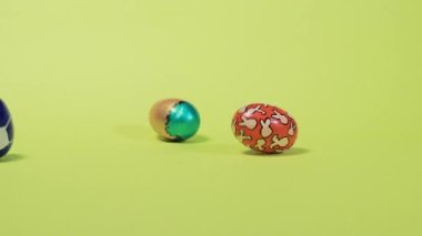 Mutlu Paskalyalar 'ın komik ve gerekli videosu. Renkli boyalı yumurtalar yuvarlanıyor ve sarı arka planda birbirlerine vuruyorlar. Bayram indirimleri ve satışlarla ilgili Paskalya tanıtımı.