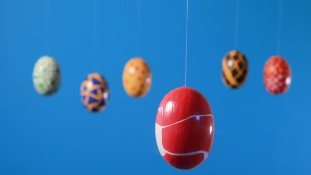 Un huevo de Pascua rojo enmascarado por un coronavirus gira y tiembla sobre un fondo médico azul. Huevos de Pascua y preparación para las vacaciones durante la pandemia de la couida. — Vídeo de stock