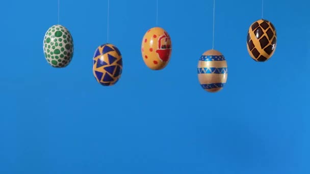 Цветные пасхальные яйца вращаются вокруг своей оси на синем фоне с местом для текста. Пасхальная продажа, скидки или промо-акции в рекламном видео. — стоковое видео