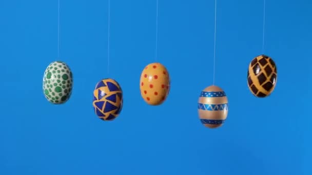 Oeufs de Pâques colorés tournent autour de son axe sur un fond bleu avec un endroit pour le texte. Vente de Pâques, réductions ou promotions en vidéo promotionnelle. — Video