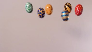 Colorful Easter eggs revolve around its axis on a beige background with a place for text. Easter sale, discounts or promotions in promotional video.