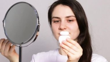 Güzel genç bir kadın dişlerini aynanın önünde diş ipiyle fırçalıyor. Ağız temizliği ve diş bakımı, diş hekimliğindeki yetişkinlerde diş çürümesinin önlenmesi