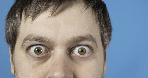 Surprised eyes of a man on a blue background with room for text to copy space. Big bulging eyes. To advertise discounts, sales, pawnshops or credit.