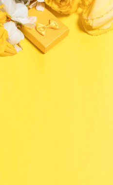 Çiçekli ve hediye kutulu sarı bir düzen. Metin pankartı için dikey yer