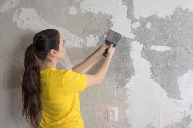 Bir kadın tamirci duvara macun koyuyor. Pürüzü lekelemek. Kendi ellerinle onar. Metin için yer.