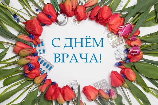 A frame of tulips and medicine tablets with inscription translation from Russian Happy Doctor\'s Day