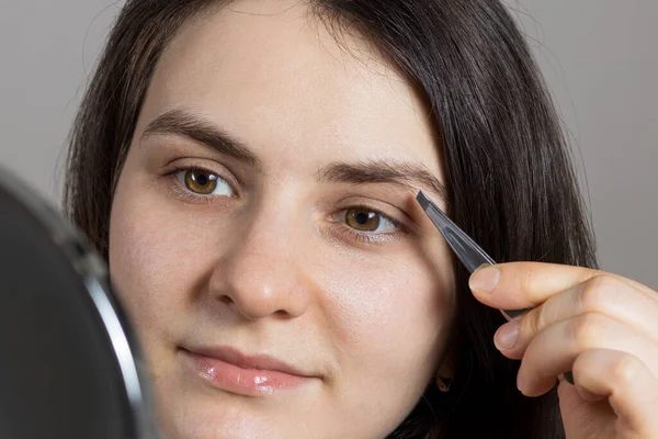 Een Brunette Plukte Haar Wenkbrauwen Voor Een Spiegel Correctie Van — Stockfoto