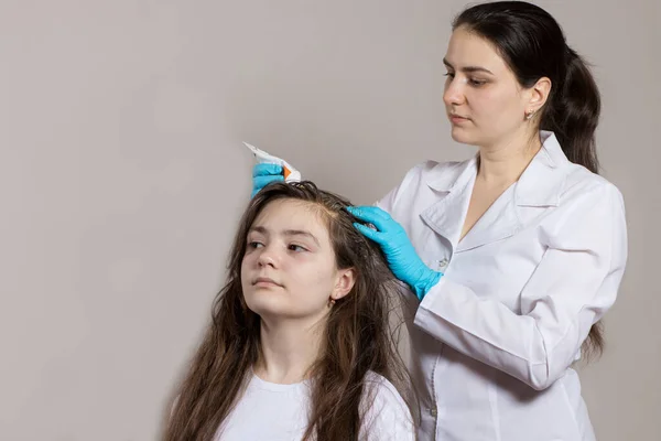 Een dermatoloog of trioloog brengt een roos of luizen onkruid aan op het haar van de patiënt. Behandeling van psoriasis, haaruitval, dermatitis of hoofdluis. — Stockfoto