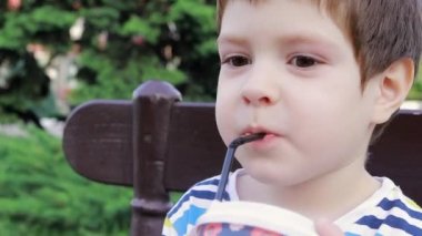 4 yaşındaki bir çocuk kentteki bir bankta plastik bardaktan kakao ya da milkshake içer. Çocuklar için sokak yemeği, tek kullanımlık sofra takımı yasağı.