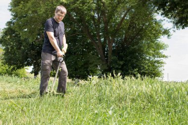Elektrikli çim biçme makinesi olan bir adam çimleri biçiyor. Bahçe malzemeleri satan bir dükkan için..