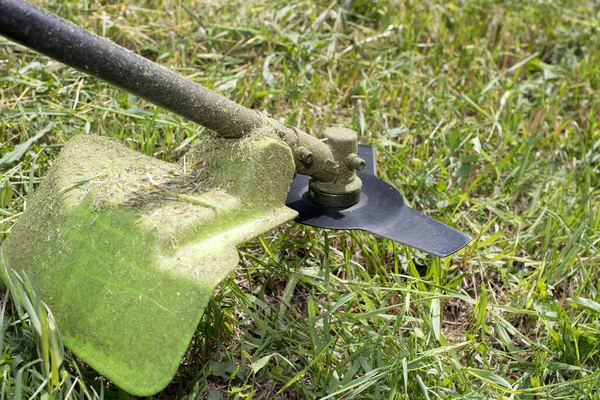 Ein handgehaltener Rasenmäher mäht das Gras im Sommer im Garten. Für ein Gartengerätehaus. — Stockfoto