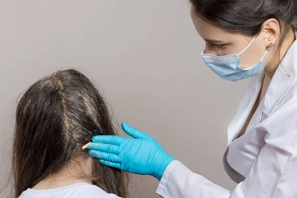 Een dermatoloog of trioloog brengt een roos of luizen onkruid aan op het haar van de patiënt. Behandeling van psoriasis, haaruitval, dermatitis of hoofdluis. — Stockfoto