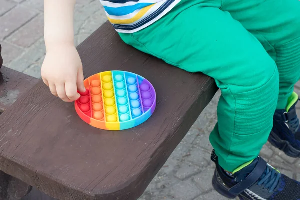 Juguete antiestrés multicolor Pop it y un niño pequeño primer plano. — Foto de Stock