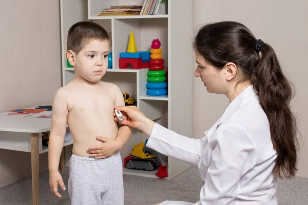 A pediatrician or nurse measures a child body temperature with a thermometer. Fever in children, colds. — Stockfoto